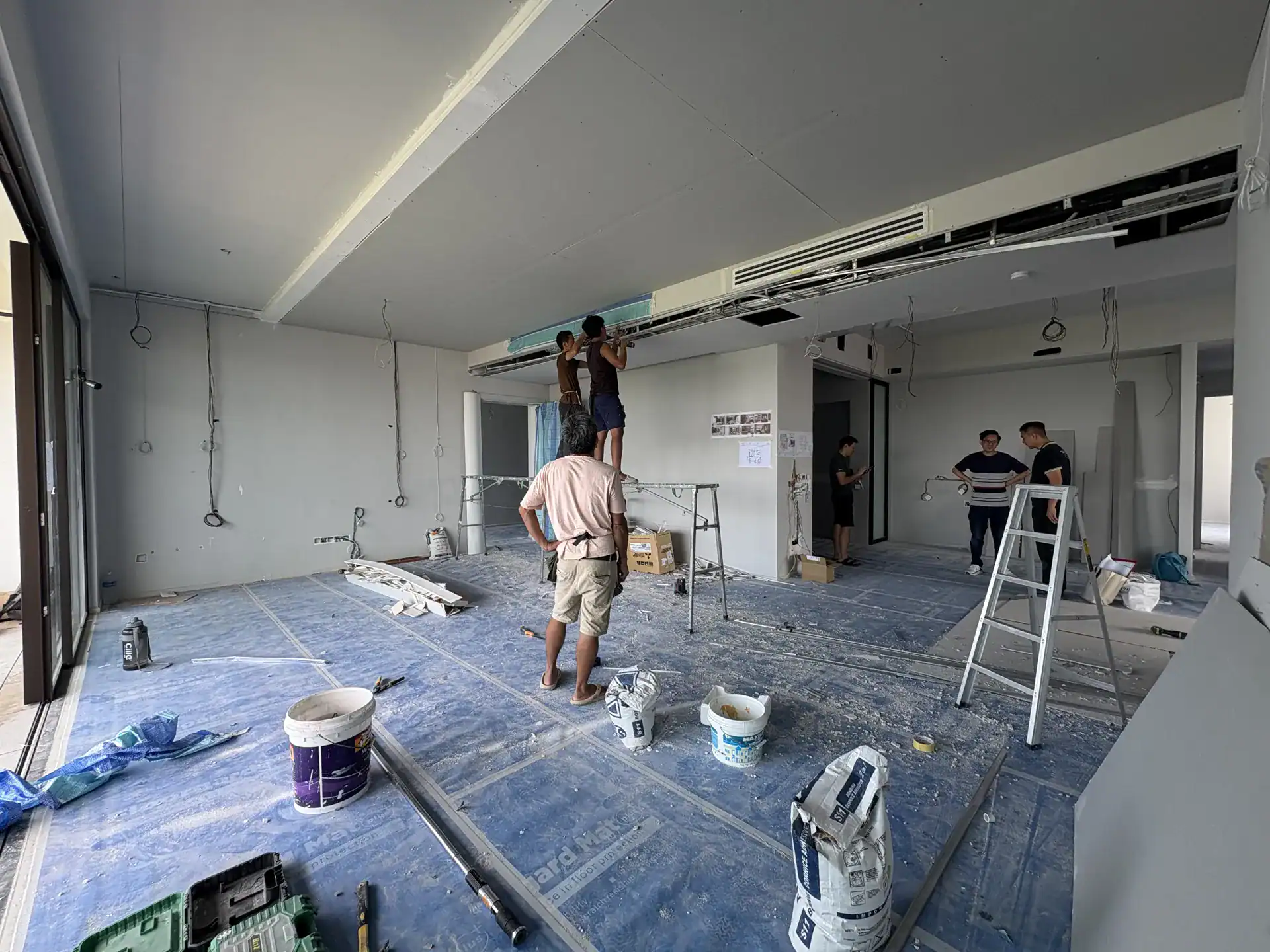 Modern office renovation in progress with team installing ceiling panels.