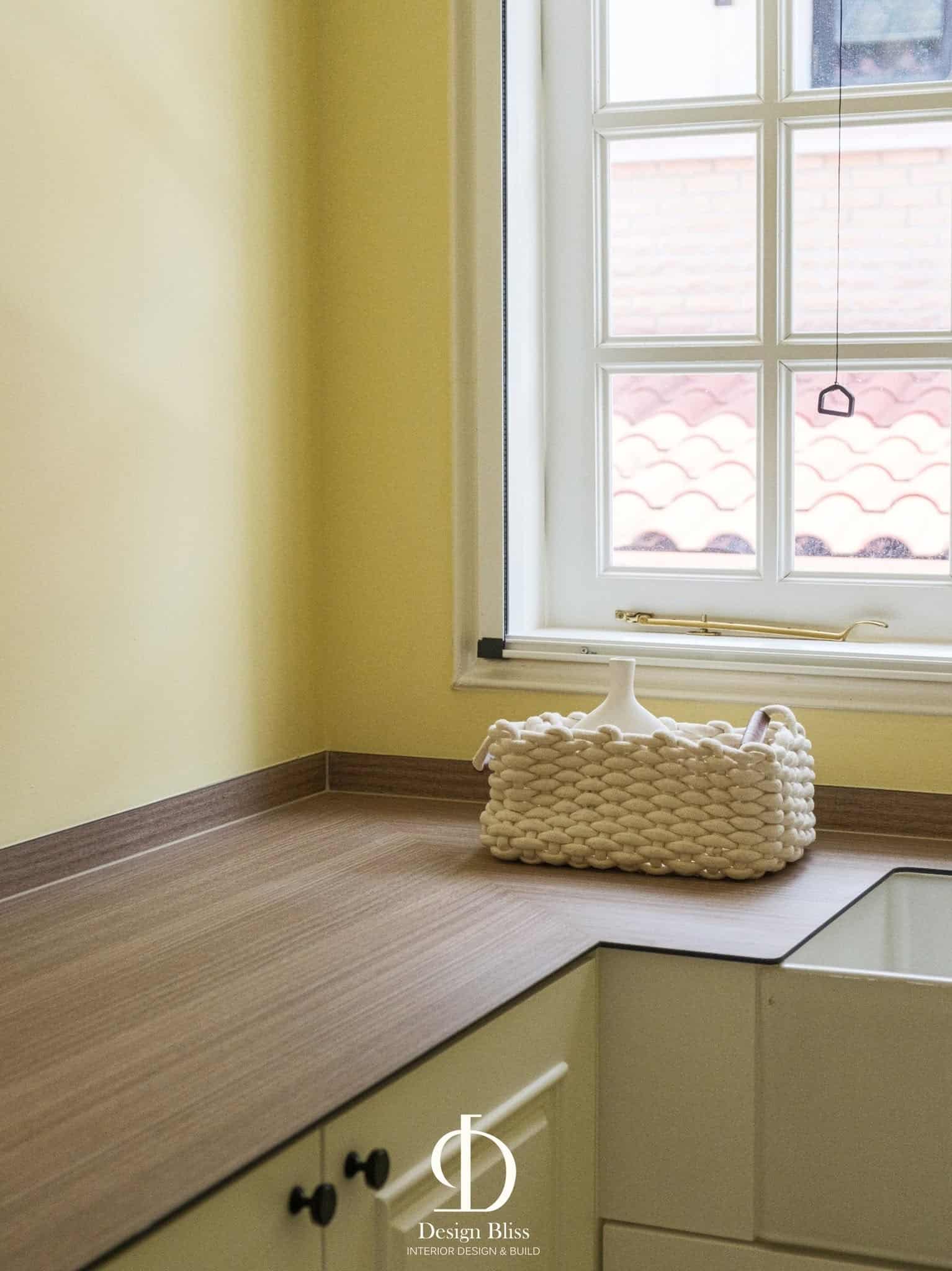 L-shaped laundry folding counter beneath the arched window at Véra Maison