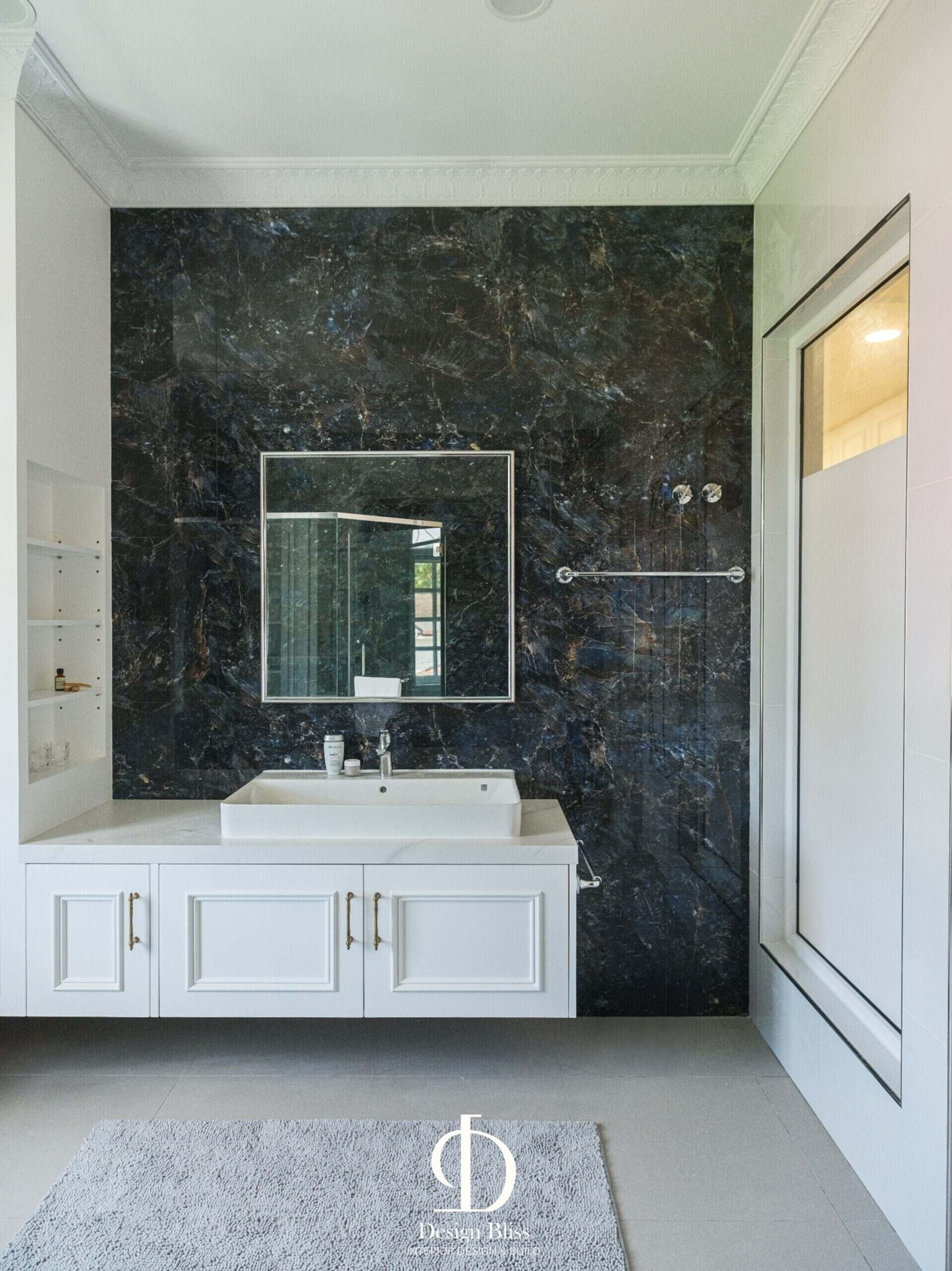 Véra Maison bathroom vanity with dark marble wall, white cabinetry and rectangular mirror