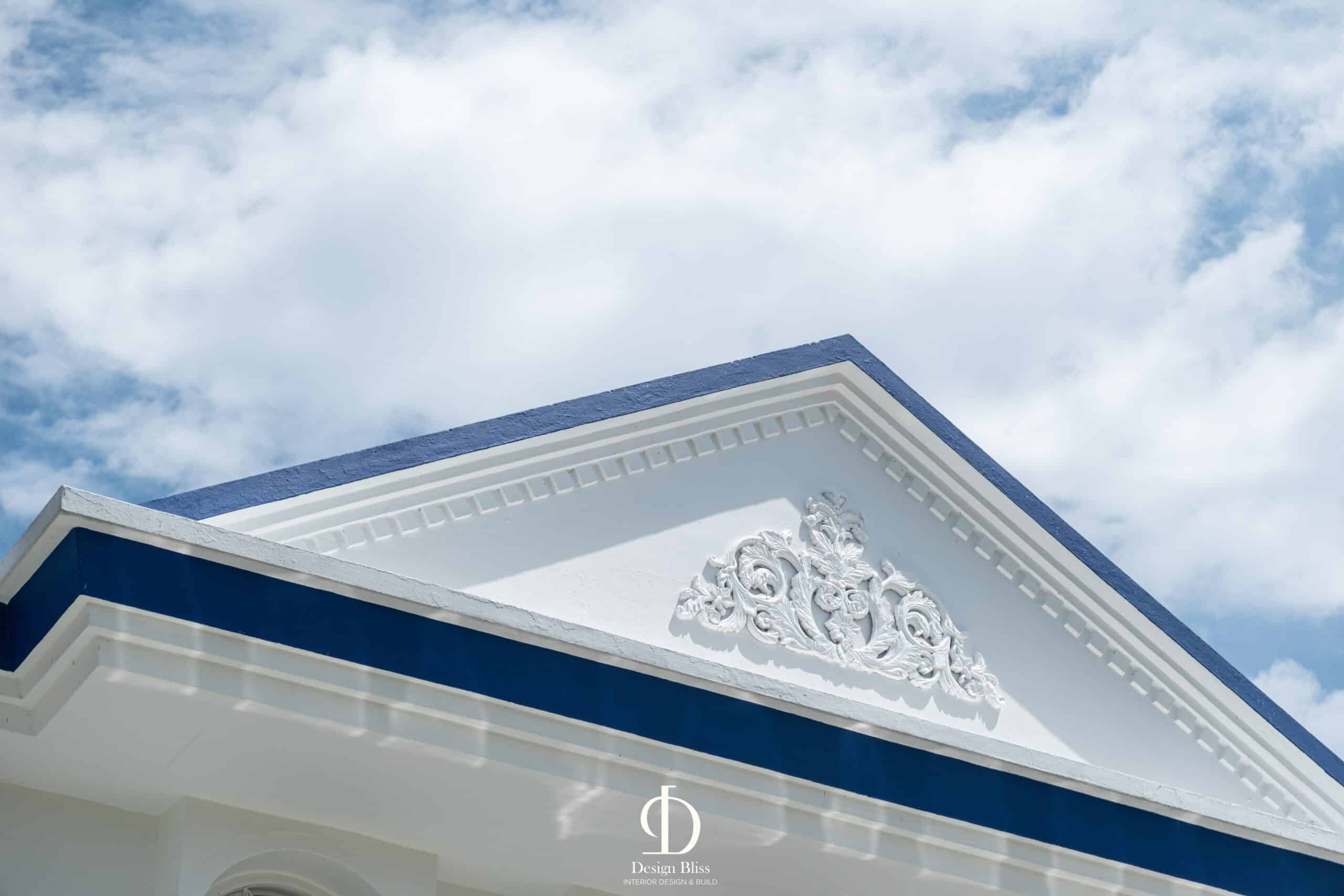 Decorative classical pediment with blue roofline detail at Véra Maison