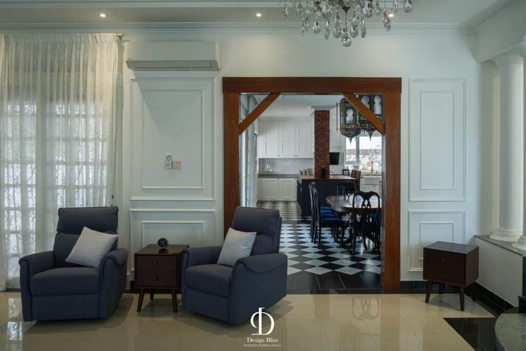 Véra Maison formal living area with blue armchairs, white wall panelling and chandelier