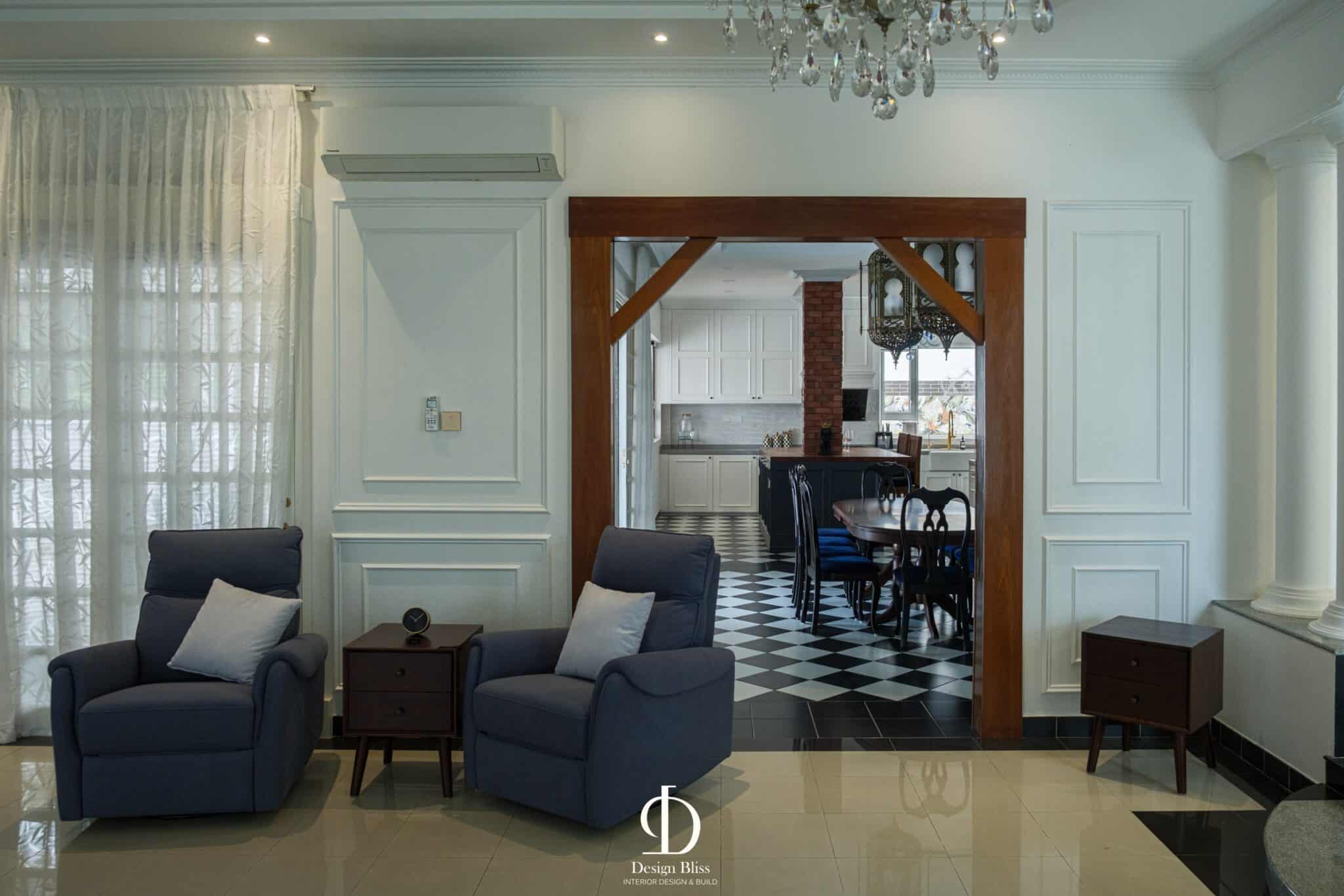 Véra Maison formal living area with blue armchairs, white wall panelling and chandelier