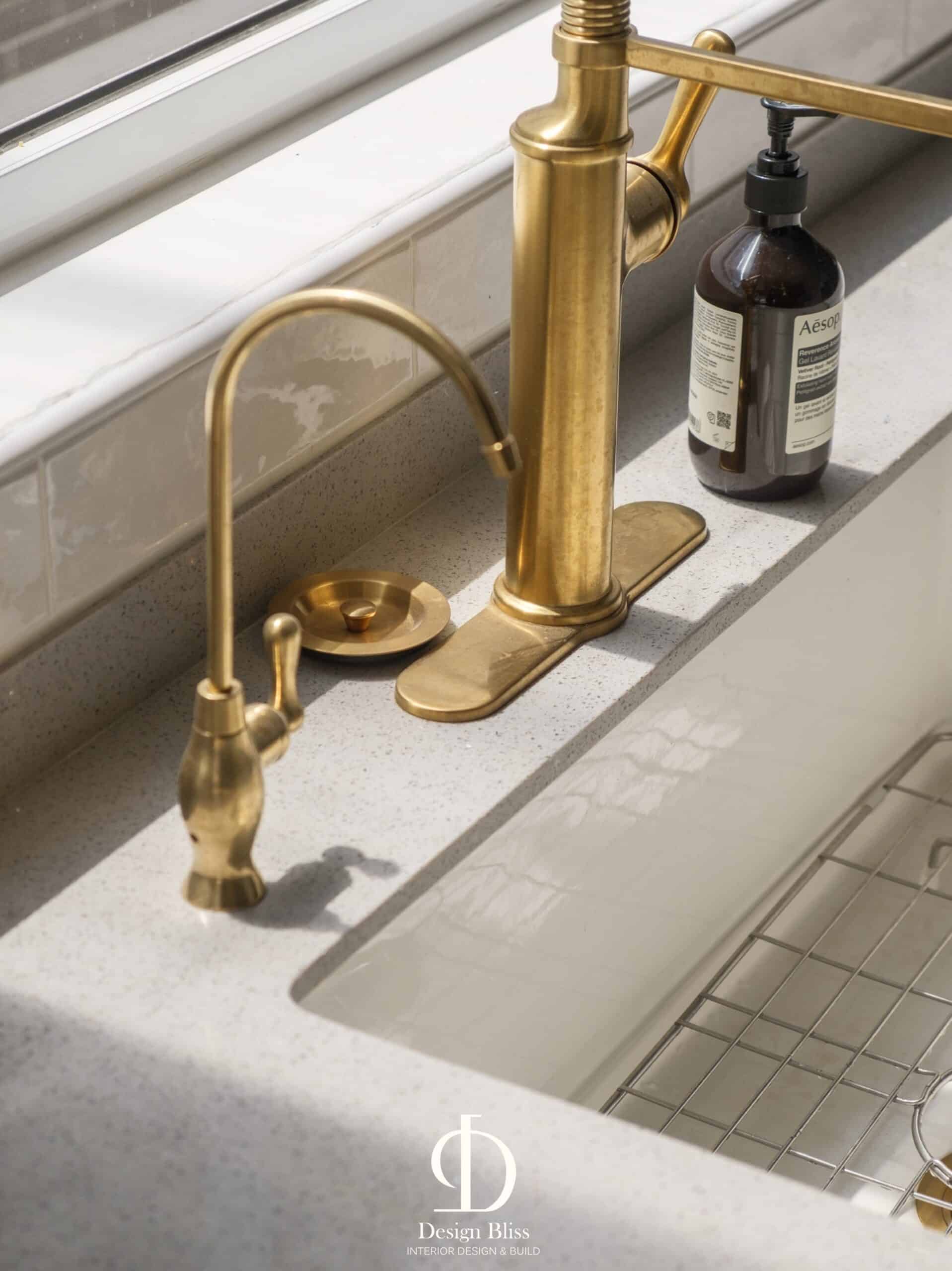 Gold-toned kitchen faucet and farmhouse sink detail at Véra Maison