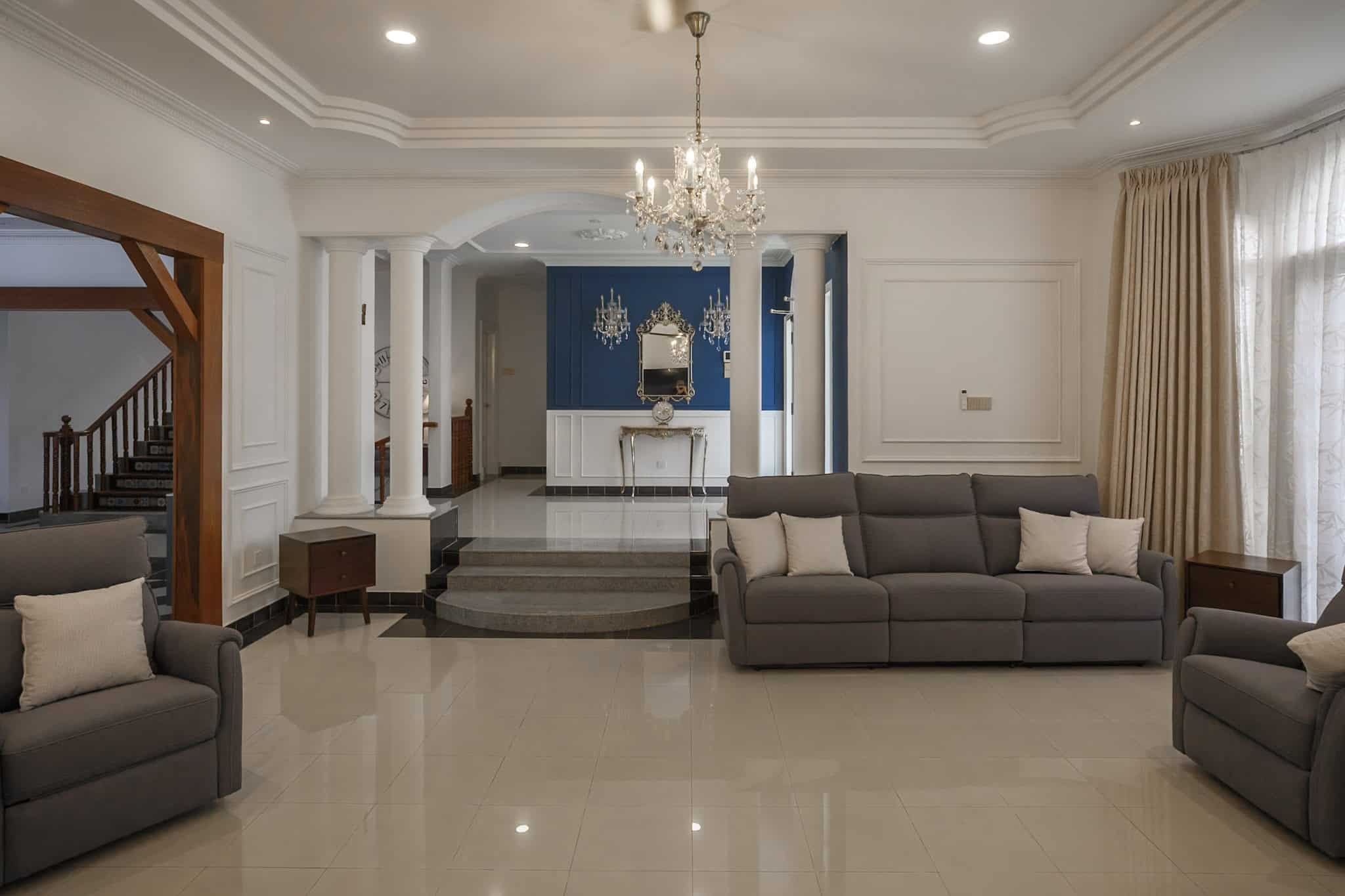 Luxury formal living room at Véra Maison with grey seating, chandelier and blue foyer