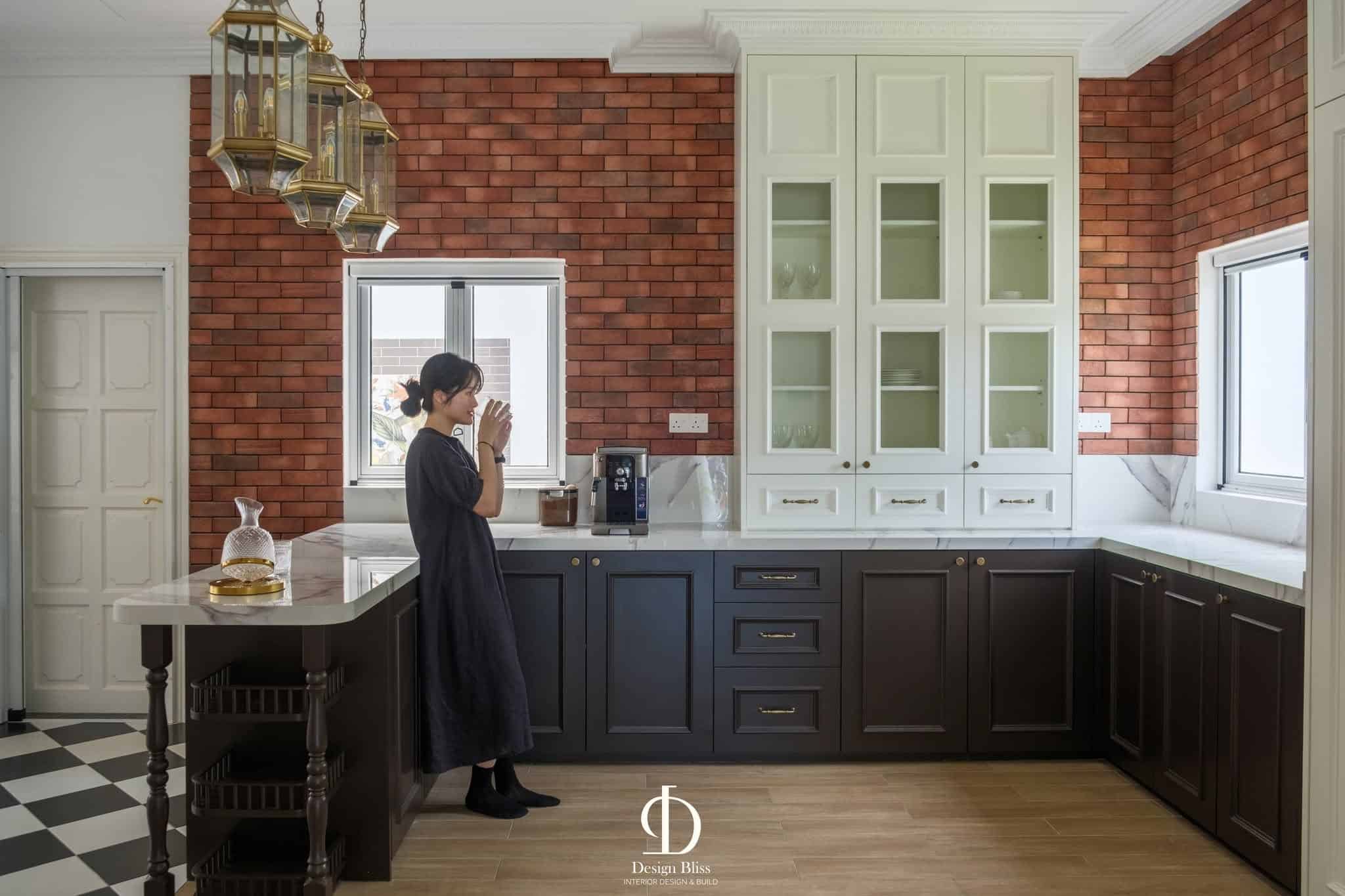 Dark kitchen cabinetry with brick wall and glass-front storage at Véra Maison