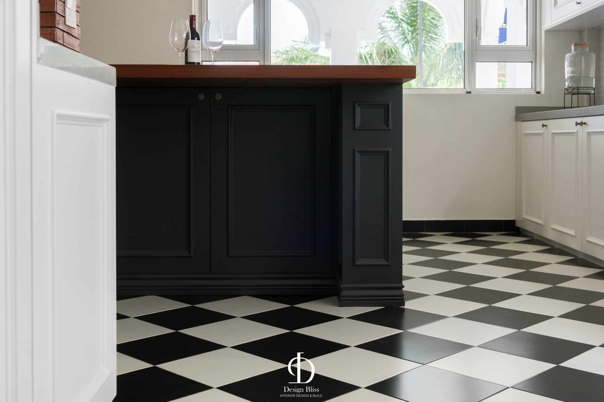 Dark kitchen island with timber worktop and black-and-white checked floor at Véra Maison