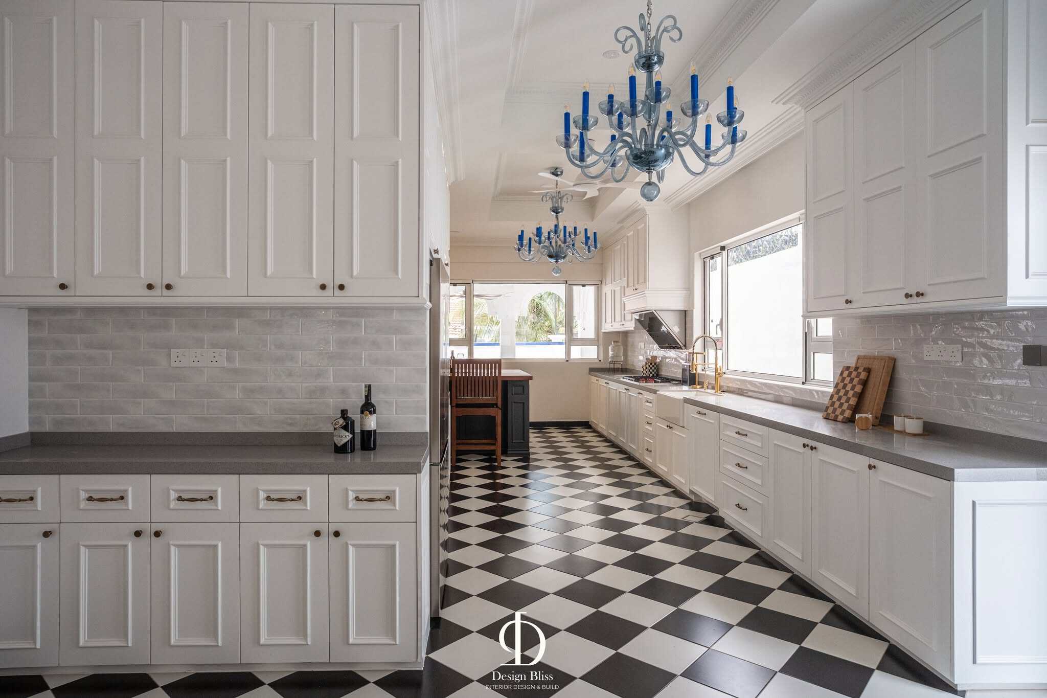White panelled kitchen cabinetry with grey backsplash and brass handles at Véra Maison